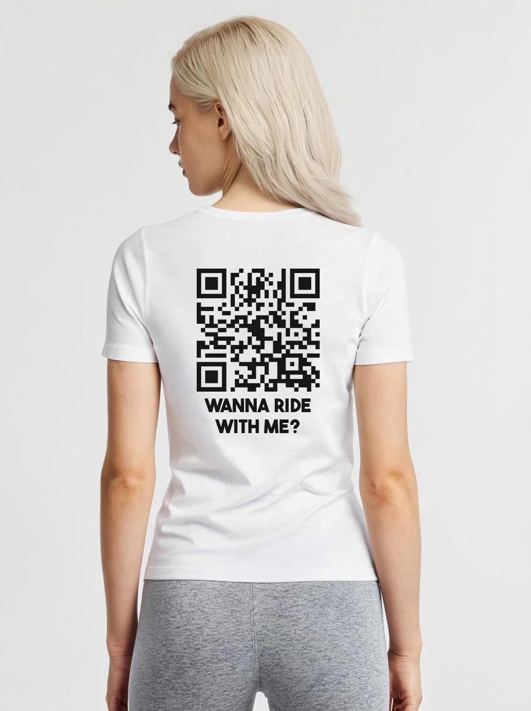 Woman wearing a white t-shirt from Cue R with a black QR code and 'WANNA RIDE WITH ME?' text on the back.